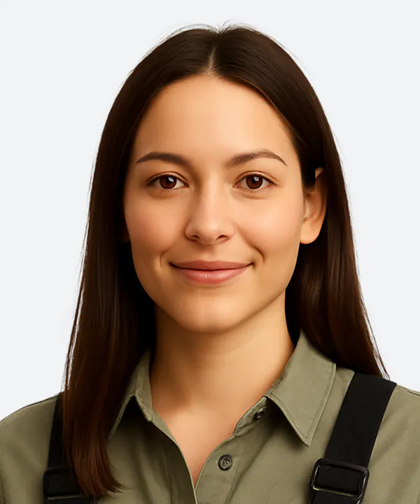 Woman with long dark hair wearing a tan and black shirt against a white background.