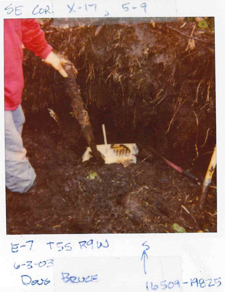 Soil core sample being examined by researcher in pink jacket, labeled with identification tags and date information.