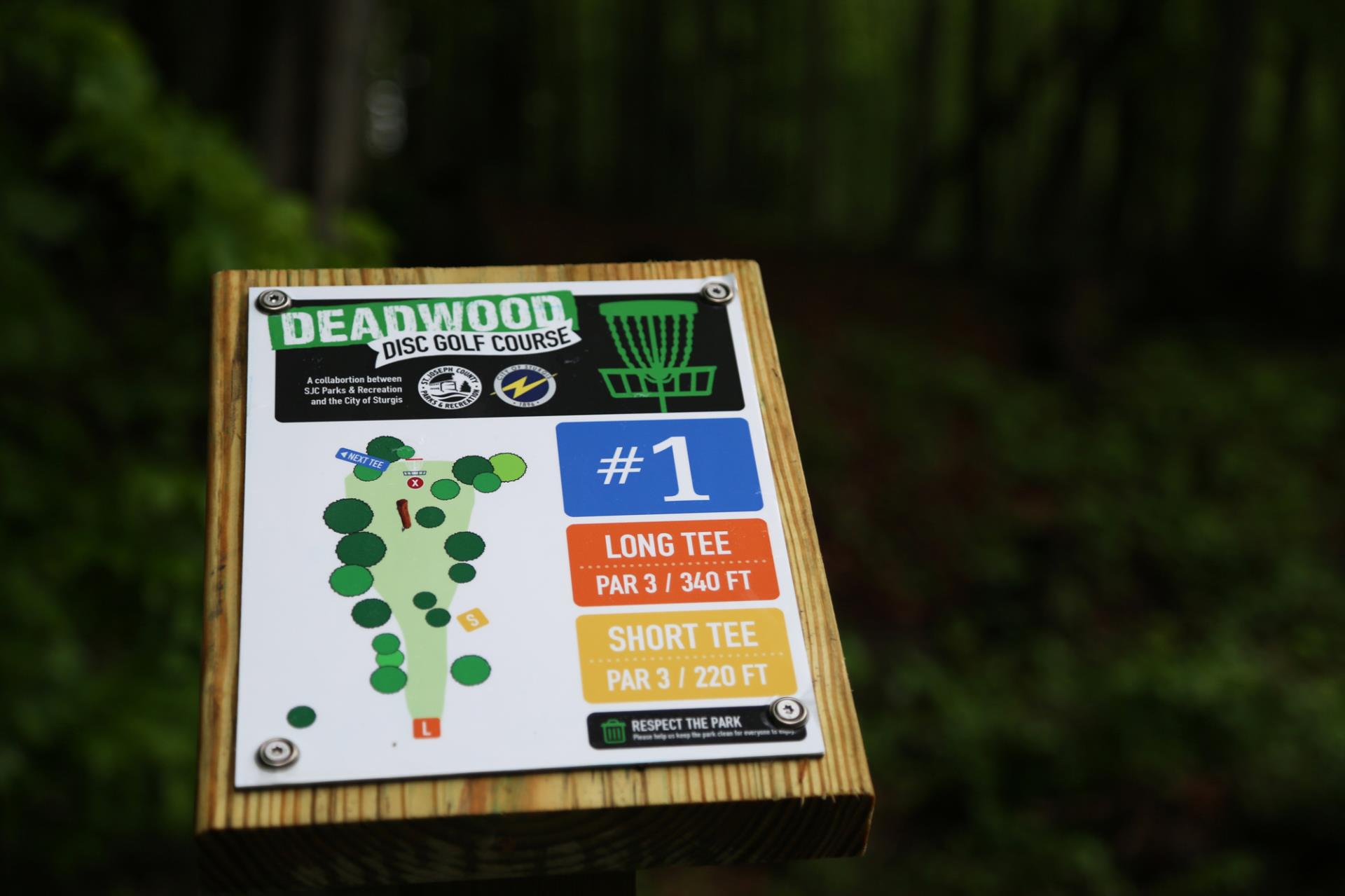 Deadwood Disc Golf Course hole #1 sign showing layout, long tee par 3/340 ft, short tee par 3/220 ft.