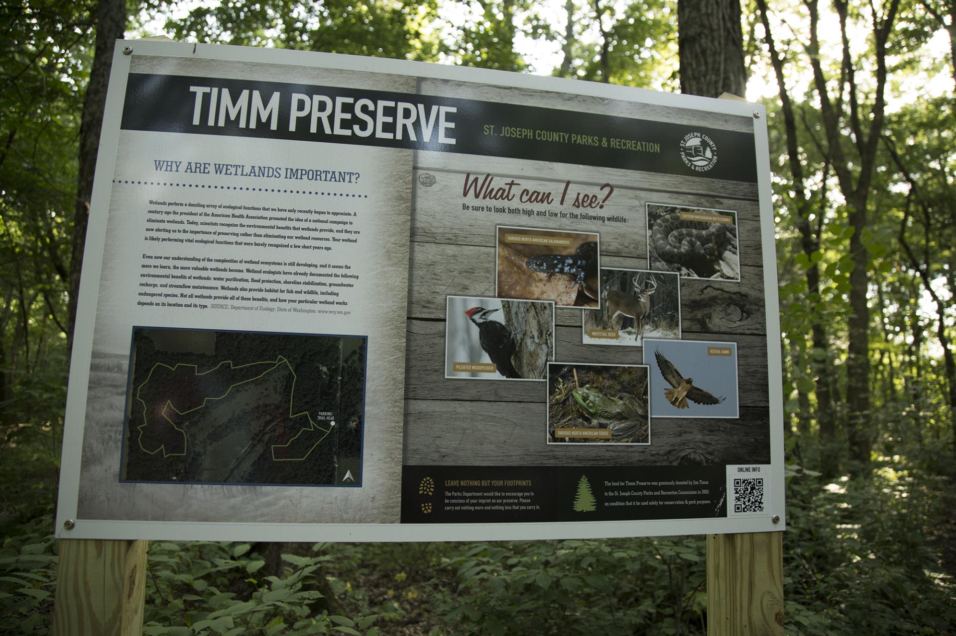 Timm Preserve informational sign displaying wetland importance, wildlife photos, and a map of St. Joseph County Parks.