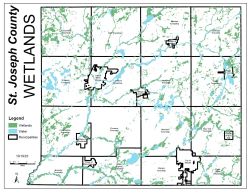 A county-wide map of St. Joseph County highlighting environmental features. Green shaded areas indicate wetlands, while light blue indicates open water bodies and river systems, showing a high concentration of wetlands along the St. Joseph River corridor.