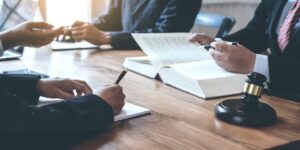 Lawyers and legal professionals reviewing documents at a conference table with a gavel and open law books.