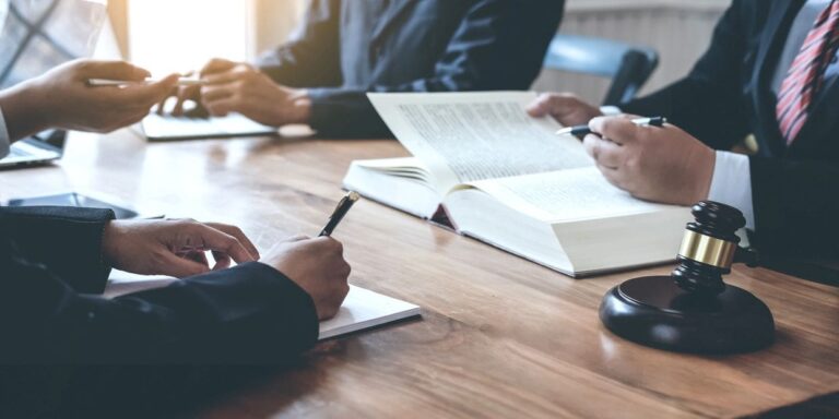 Lawyers and legal professionals reviewing documents at a conference table with a gavel and open law books.